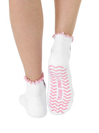 White socks with pink lining, equipped with stay-put grips to prevent slipping, featuring a small ballet-themed print, shown worn on a white background.