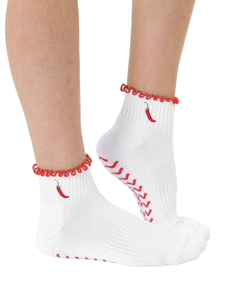 White socks with super sticky, stay-put grips to help prevent slipping, featuring a small chili pepper print worn on a white background.