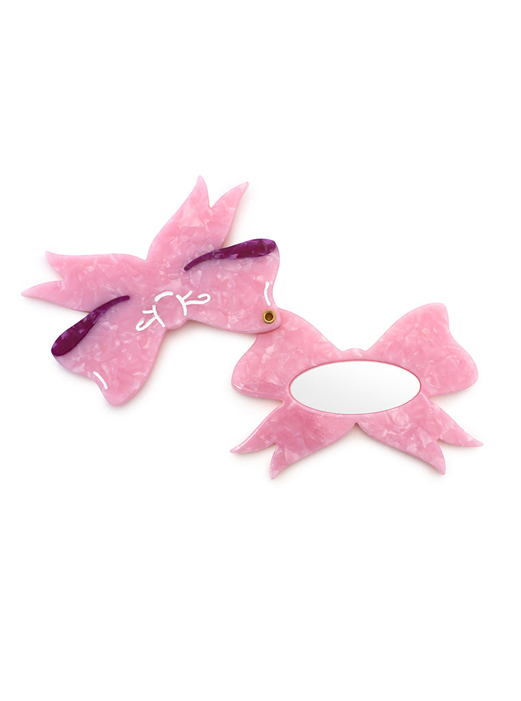 Pink compact mirror with a bow design, perfect for quick touch-ups on the go, displayed on a white background.