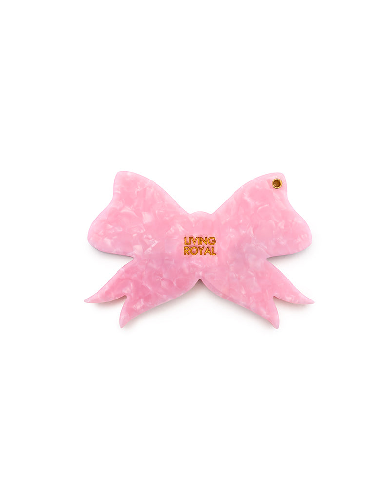Pink compact mirror with a bow design, perfect for quick touch-ups on the go, displayed on a white background.