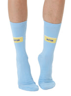 Light blue socks with yellow 'BUTTER' text worn by a person on a white background
