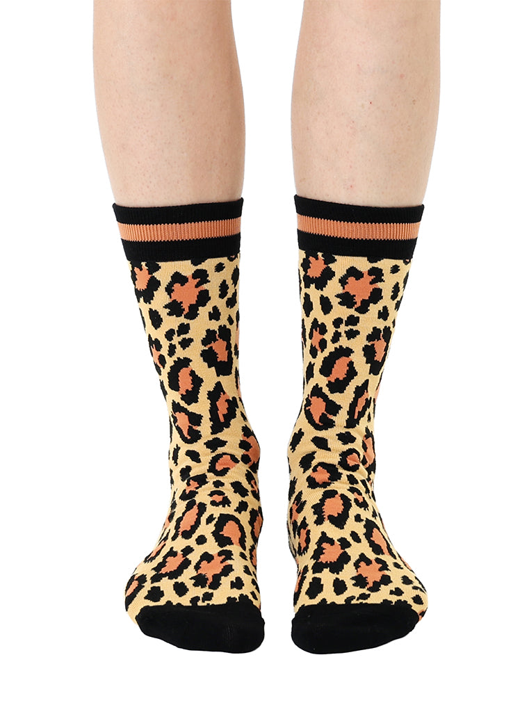 Women’s bamboo crew socks with a cheetah print pattern, shown worn on a person against a white background.