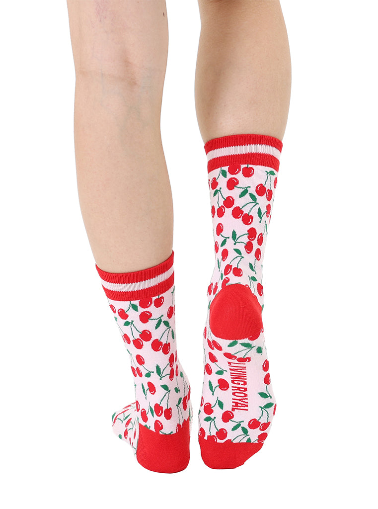 Red and light pink women’s bamboo crew socks featuring a cherry-themed pattern, shown worn on a person against a white background.