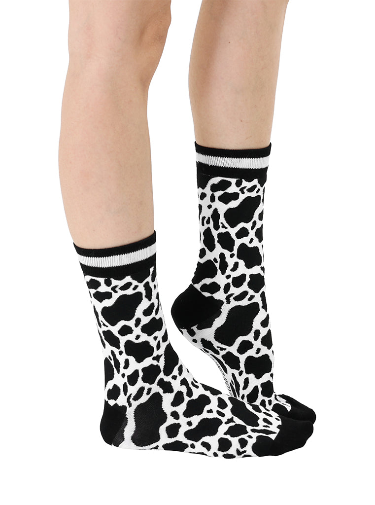 Women’s bamboo crew socks with a cow print pattern, shown worn on a person against a white background.