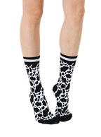 Women’s bamboo crew socks with a cow print pattern, shown worn on a person against a white background.