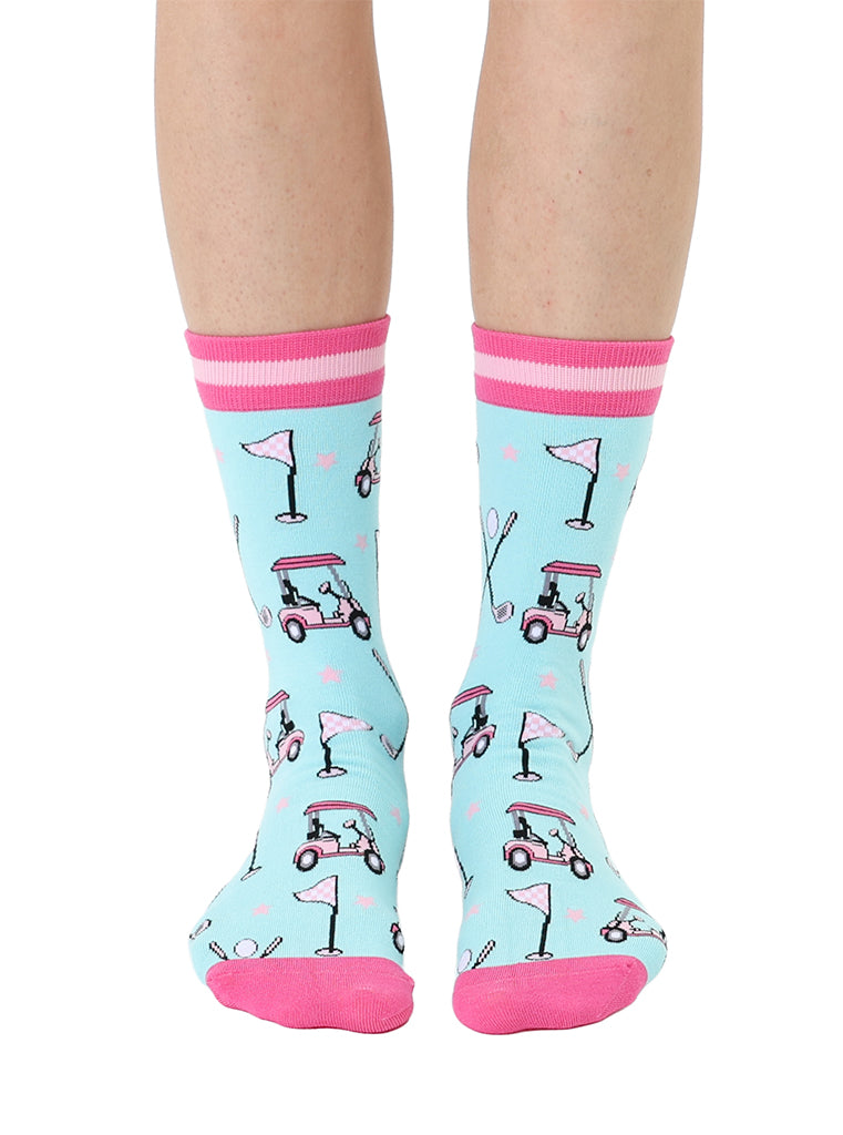 Light blue women’s bamboo crew socks with pink-striped cuffs, featuring a playful golf-themed print, shown worn on a person on a white background.