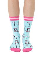 Light blue women’s bamboo crew socks with pink-striped cuffs, featuring a playful golf-themed print, shown worn on a person on a white background.