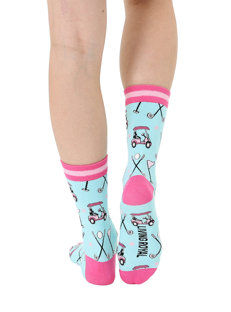 Light blue women’s bamboo crew socks with pink-striped cuffs, featuring a playful golf-themed print, shown worn on a person on a white background.