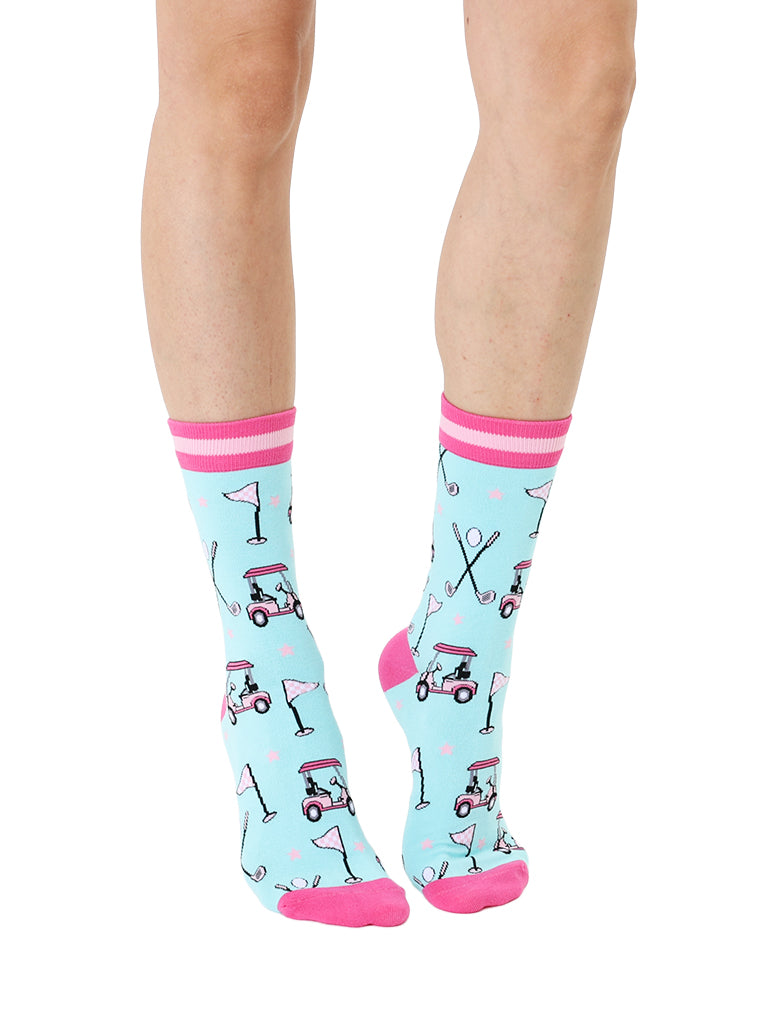 Light blue women’s bamboo crew socks with pink-striped cuffs, featuring a playful golf-themed print, shown worn on a person on a white background.