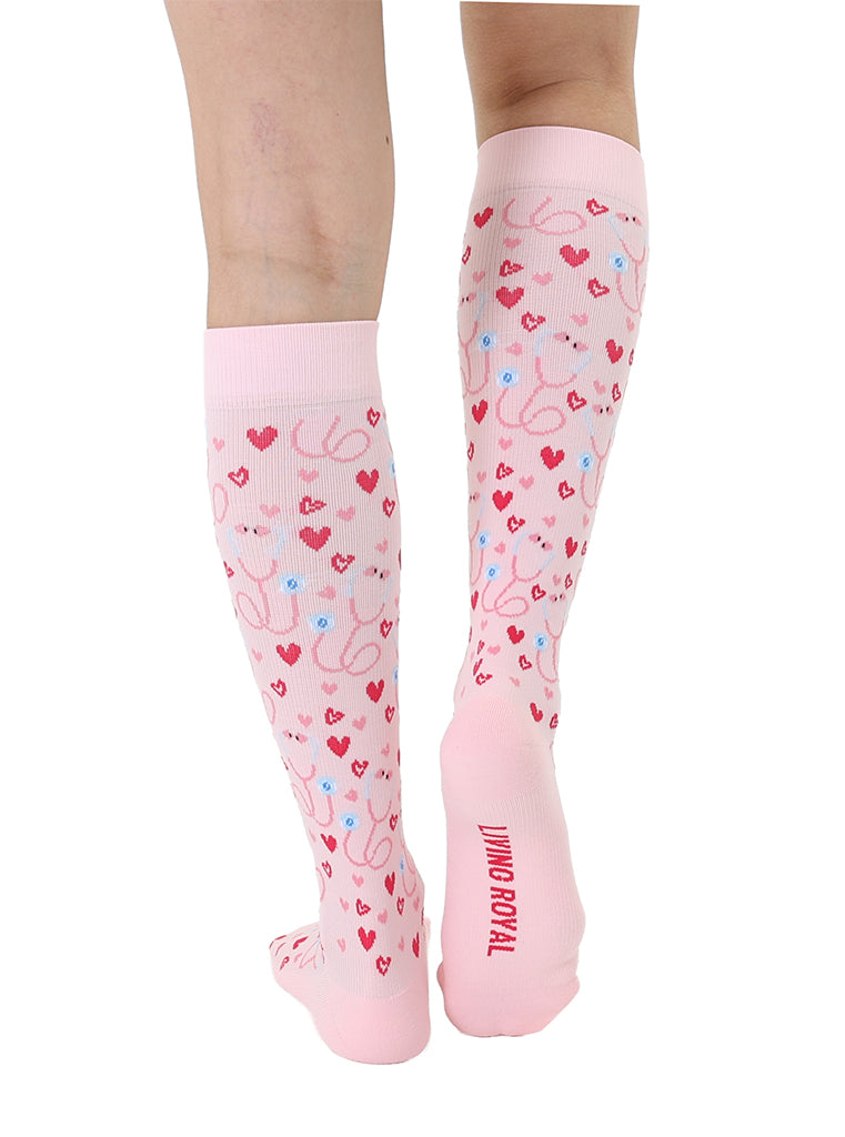 Pink padded compression socks featuring a stethoscope and hearts pattern, shown worn on a white background.